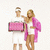 Two people stand side-by-side holding a pink rectangular object, with text in bright pink pixelated font on white background.