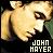 Pixelated close-up of a person with light brown hair and dark eyes, wearing black clothing against a gradient background. Text reads 'JOHN MAYER' in blocky white letters at bottom right.