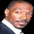Static pixelated image of a person's head and shoulders in formal attire against black background