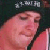 Pixelated close-up of a person with closed eyes wearing a dark cap and pink garment against a dark background.