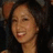 A static pixelated image shows a person with dark hair and light skin smiling broadly, wearing a dark top against a blurred background.