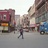 Pixelated static image shows a street scene with buildings, a person walking, and a vehicle on the right.