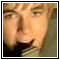 Pixelated close-up of a person's face with light brown hair and neutral expression, framed by black border on white background.