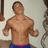 A pixelated image of a shirtless man with short brown hair wearing blue shorts, standing against a light background.