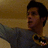 A person in a gray long-sleeve shirt with a Batman logo on the chest, positioned against a beige background with arms extended.