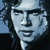 Pixelated static image of a person's face with dark hair and light skin tones, rendered in blue-gray color palette against dark background.