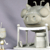 A pixelated static image shows a light gray giraffe head with closed eyes resting on a white railing against a muted purple background.