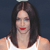 A pixelated close-up of a person with long dark hair wearing a white sleeveless top against a dark blue background.