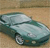 Static pixelated image of a light blue sedan with dark green accents on a beige background, viewed from a low angle.