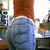 Static pixelated image of a person viewed from behind wearing blue jeans and a brown top, standing in an indoor setting with furniture.