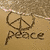 A pixelated image of a peace symbol drawn in sand with the word 'peace' below it, next to green text spelling 'peace'.