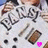 Pixelated image of a person in white clothing holding multiple objects including a brown rectangular item and dark circular items, with a small pink heart shape visible.