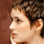 Pixelated profile view of a person with short brown hair against a solid brown background, showing side of face and ear.