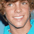 Pixelated close-up of a smiling person with brown hair wearing a light blue shirt against a gradient background.