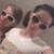 Two pixelated figures in white tank tops wear dark sunglasses, positioned side-by-side against a muted gray background.
