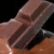 Pixelated close-up of a figure's lower face and neck with brown hair, dark eyes, and light skin against black background.