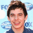 Pixelated image of a person with dark hair and light skin wearing a dark blue shirt against a light blue background with partial text.