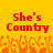 Red pixelated text 'She's County' on a yellow background with orange flame-like patterns below.