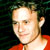 Static pixelated image of a person's face and upper torso in red clothing against dark background with greenish hints.