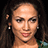 Pixelated close-up of a person with light skin tone, dark eyes, and long curly brown hair against black background.