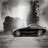 Pixelated grayscale image of a dark vehicle on a light background with two vertical structures and a bright central glow.