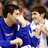 Two people in blue and white sports jerseys embrace on a blue background with orange pixelated text.