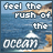 A static image of a beach scene with text overlay reading 'feel the rush of the ocean' in pixelated font, featuring blue water and rocky cliffs.