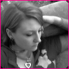 Black-and-white image of a person with short hair resting on a couch, wearing a star-shaped pendant necklace and dark clothing.