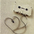 A pixelated static image shows a light-colored figure with dark eyes and mouth, holding a heart-shaped object against a beige background.