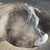 A pixelated circular icon with a central light brown area and dark brown edges, featuring a white and gray abstract shape on the right side.