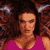 Pixelated static image of a person with voluminous curly hair wearing a magenta top, set against a dark background with blurred figures on either side.