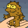 Brown cartoon monster with large yellow eyes and small horns stands on a light-skinned hand against a blue background.