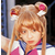 Pixelated static image of a character with long light brown hair, wearing a pink and white outfit with blue accents and large ear-like accessories featuring red inner sections.