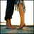 A person's lower legs and feet in dark pants and bare feet, standing on a reflective surface with a bright background.
