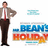 Pixelated image of Mr. Bean character in brown suit with red tie, standing with hand on hip next to 'Mr. Bean's Holiday' text on white background, with green text overlay reading 'you speak very good french' and 'gracias'.