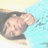 Pixelated static image of a light-skinned figure with closed eyes and short hair, partially obscured by dark shapes against a gradient background.