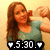 Pixelated image of a person with long brown hair wearing a green sleeveless top, holding an object near their face against a light background.