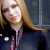 A static image shows a person with long light brown hair wearing a dark zip-up jacket over a red and black checkered shirt, with text reading 'avril fan' in pixelated white letters on a black background.