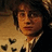Pixelated image of a person with dark hair and glasses on left, red background with pixelated text on right.