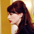 Pixelated profile of a person with dark brown hair and red lips against a yellow background, wearing a white top and dark outer garment.