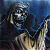 Pixelated static image of a dark figure with metallic elements against a blue background, featuring indistinct facial features and ambiguous shapes.