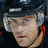 Pixelated image of a person wearing a dark helmet with white accents, next to orange background text reading "Mike Comrie #89".