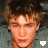 A pixelated image of a person with light brown curly hair wearing a gray jacket, showing two states: one with a white downward-pointing arrow icon and another with a white heart outline icon.
