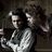 Two figures in a dimly lit setting with one figure holding a dark object, next to pixelated text reading "Sweeney Todd And Mrs. Lovett" on a black background.
