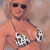 Static pixelated image of a person in a bikini top with sunglasses and light-colored hair against a muted background.