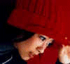 Animated sequence showing a person in red knit hat and dark jacket with white zipper, transitioning from downward gaze to upward gaze against solid red background.