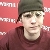 A pixelated portrait of a person wearing a dark beanie and maroon hoodie against a red background with white text fragments.