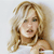 Pixelated image of a person with long blonde hair wearing a white top, set against a light background.