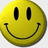 A pixelated yellow smiley face with black oval eyes and a curved black mouth on a light gray background.