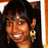 Pixelated close-up of a person with dark hair, light brown skin tone, and a smiling expression wearing large gold earrings.